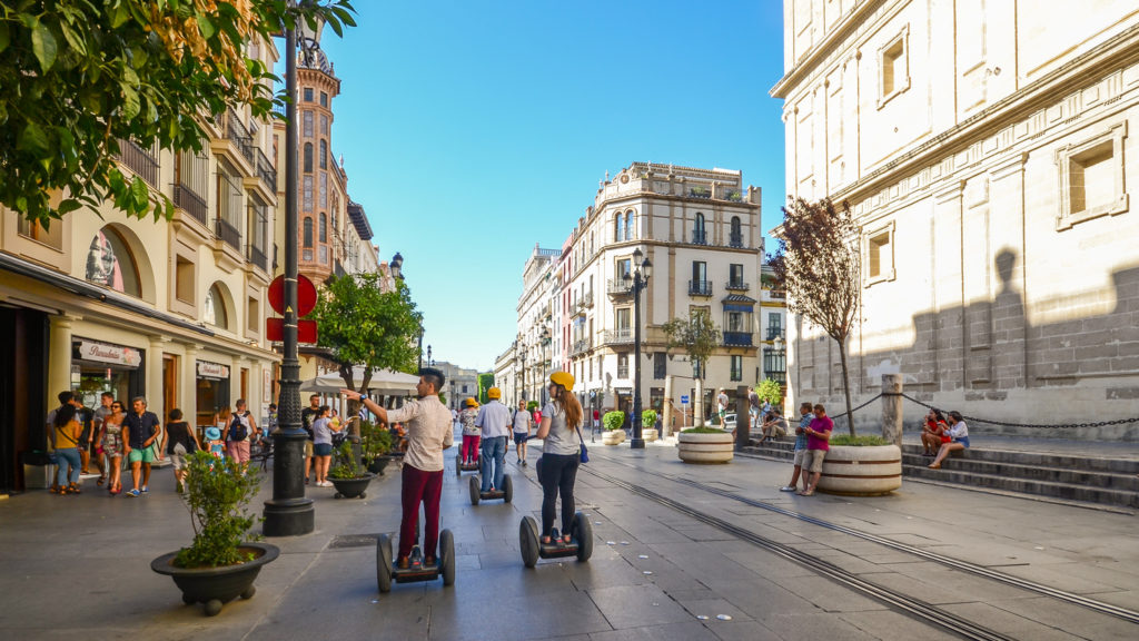 Tourists on segways at Av. de la Constitucion in the historic centre of Seville, Andalusia, Spain